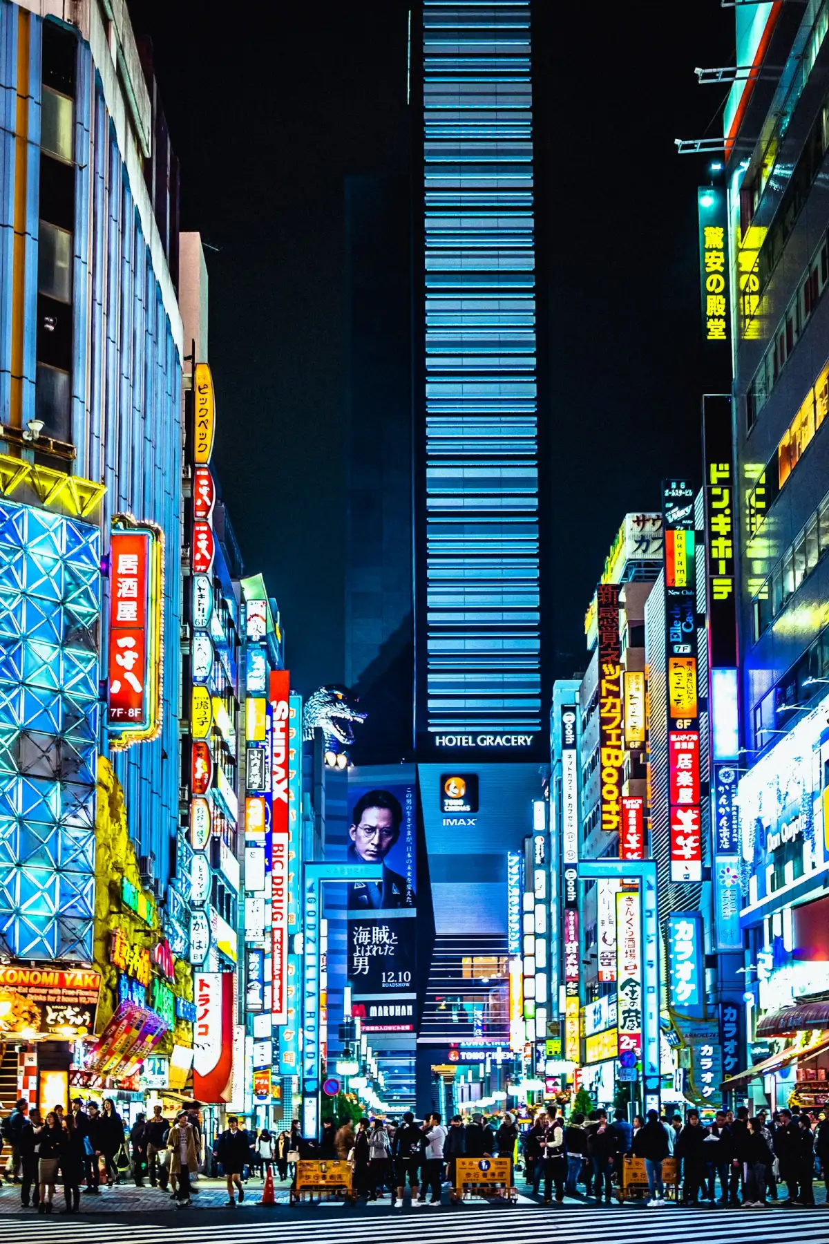 Busy street at night lined with illuminated digital signs and screens