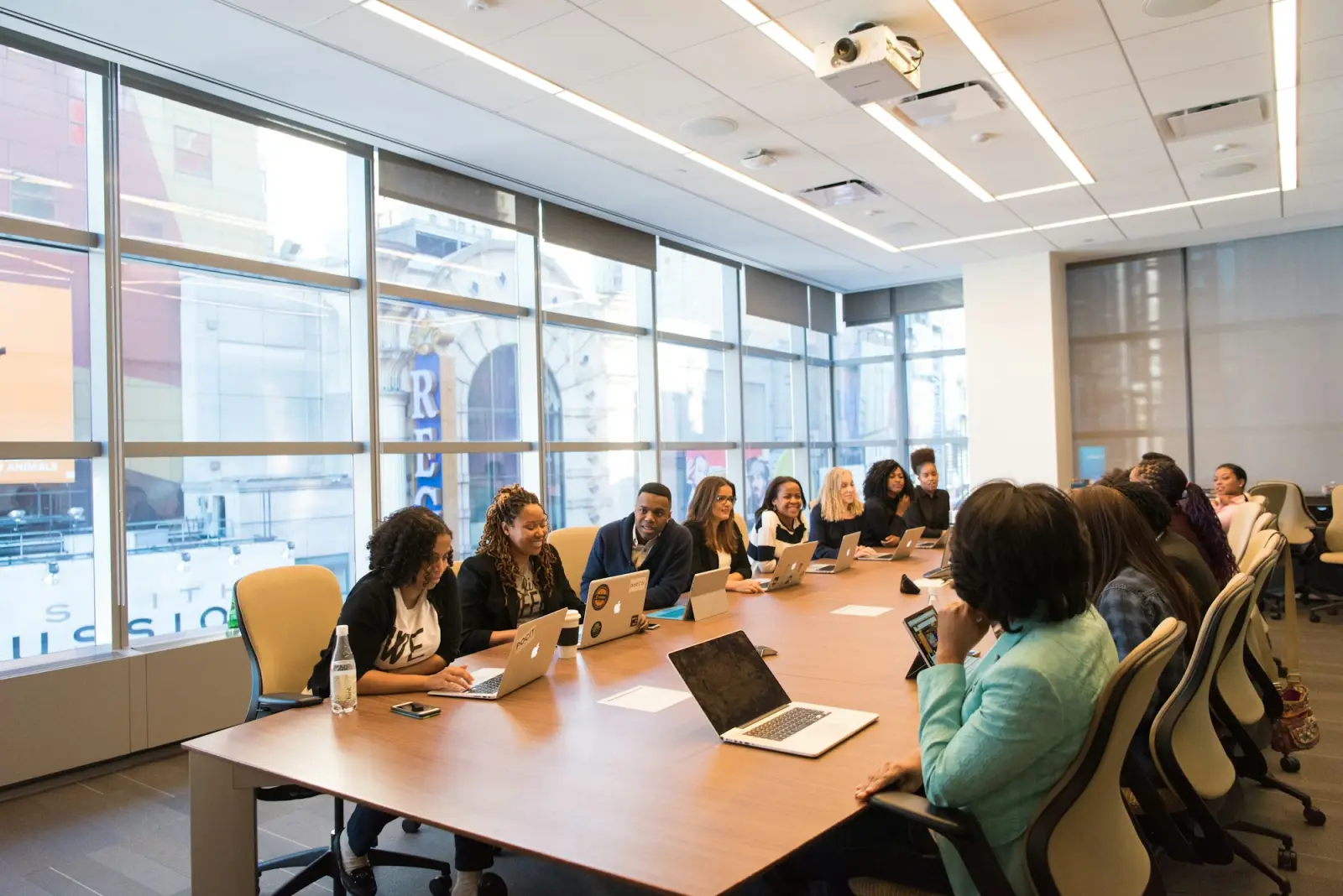 Meeting room with a ceiling-mounted projector and people seated around a conference table