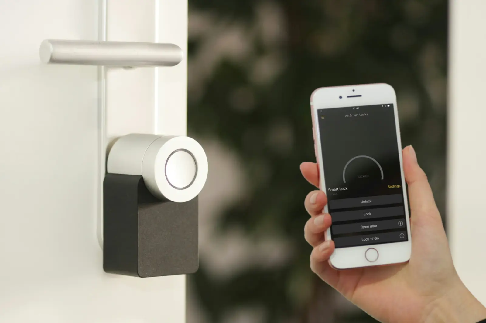 Electronic door lock beside a hand holding a smartphone used to release the door